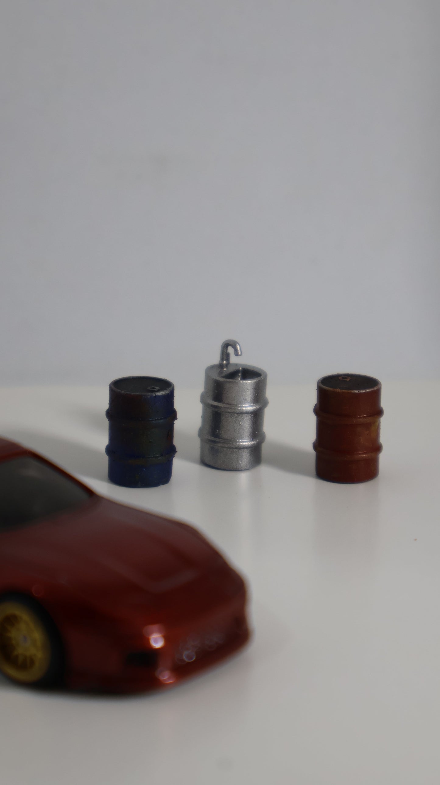Barriles miniatura 1:64 junto a auto die-cast para escala de referencia
