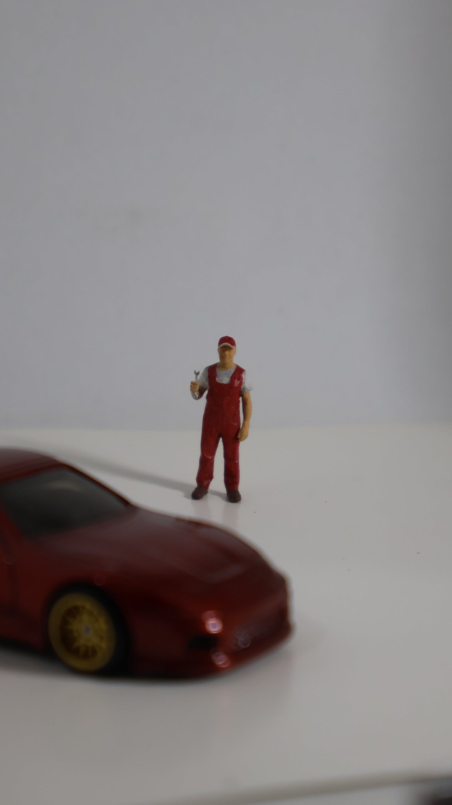 Figura mecánico miniatura 1:64 junto a auto die-cast para escala de referencia