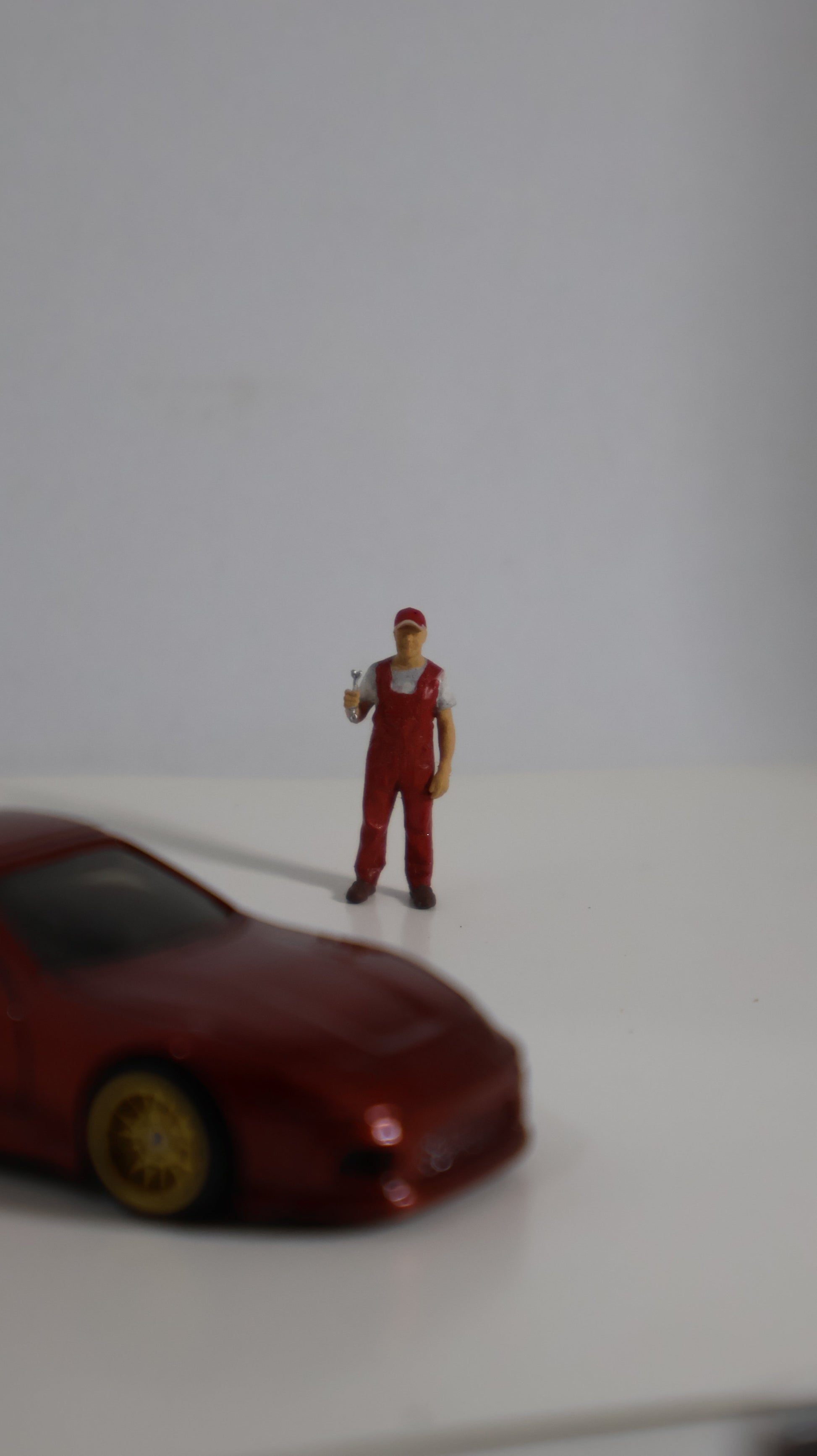 Figura mecánico miniatura 1:64 junto a auto die-cast para escala de referencia